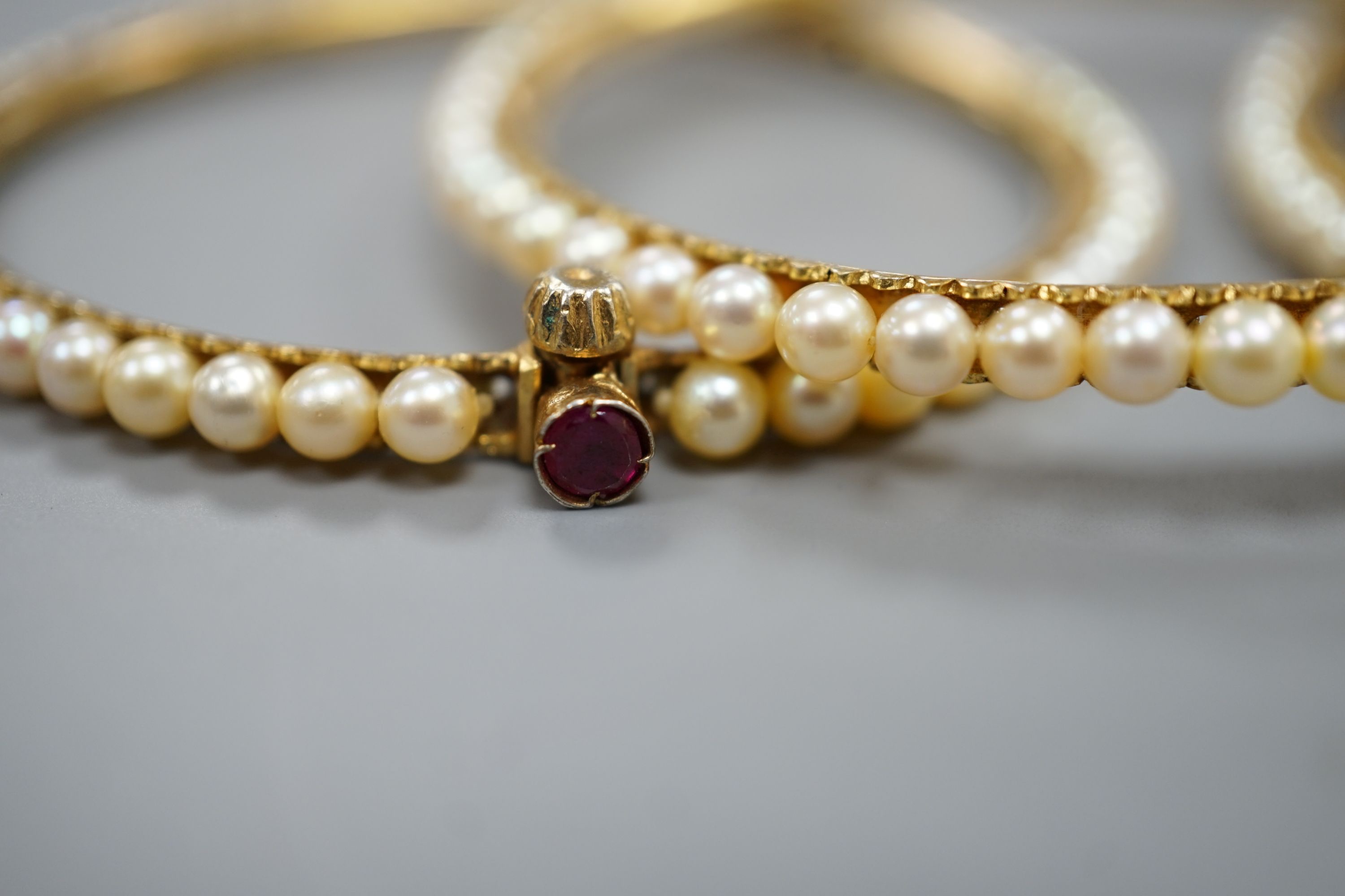 Three gilt white metal and cultured pearl set bangles.